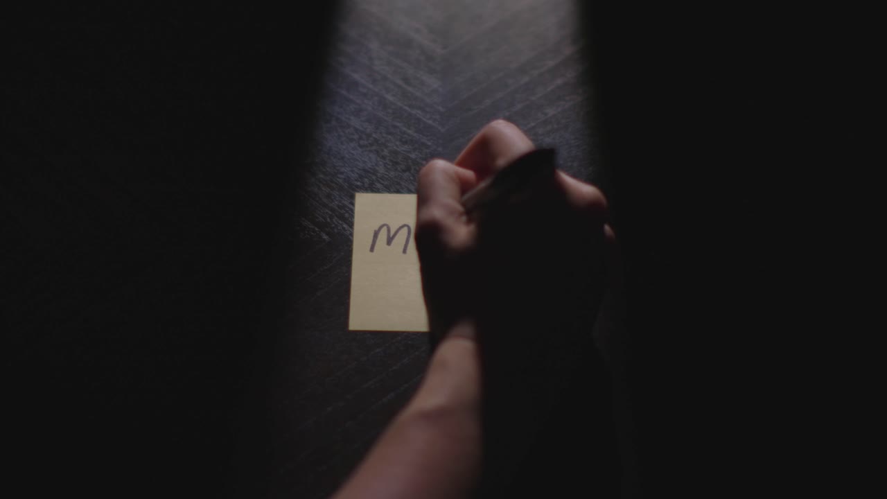 "Murder" written on a Sticky Note with a sharpie and placed on a table under dramatic lighting