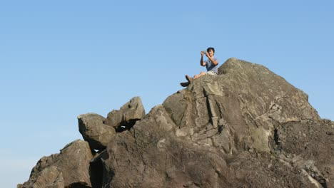 Lower-view-of-man-sitting-on-the-top-of-the-hill