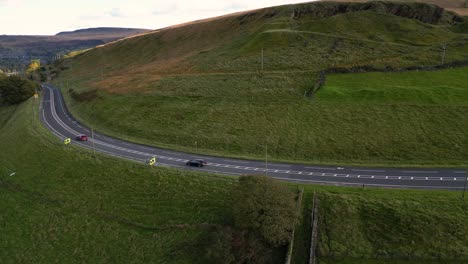 Cars-passing-on-road-across-rural-hill