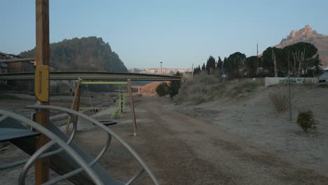 Schwenkaufnahme-Von-Rechts-Nach-Links-Eines-Verlassenen-Spielplatzes-In-Der-Nähe-Einer-Brücke,-Luftaufnahme