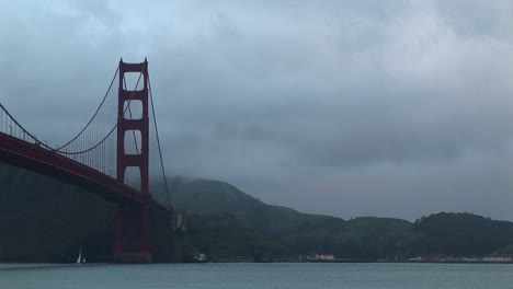 the stark geometric shapes of the golden gate bridge contrasts with natural beauty of fog on san francisco bay