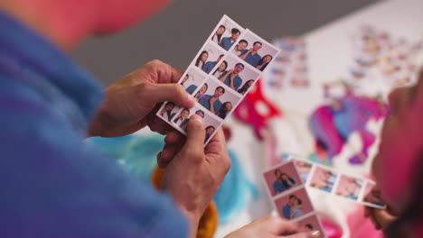 close up of a group of friends having fun looking at prints from photo booth with props 9