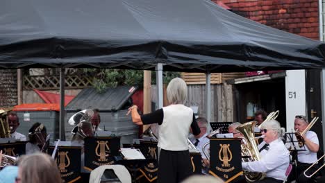 conductor leads brass band under a canopy