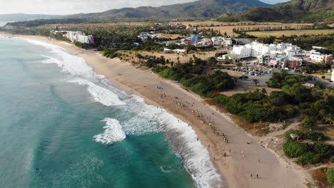 a drone shot of philippine sea and surfers on the beach in kenting national park, taiwan with camera approaching the beach