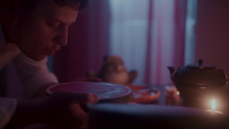 man enjoying watermelon and tea in a serene night setting.