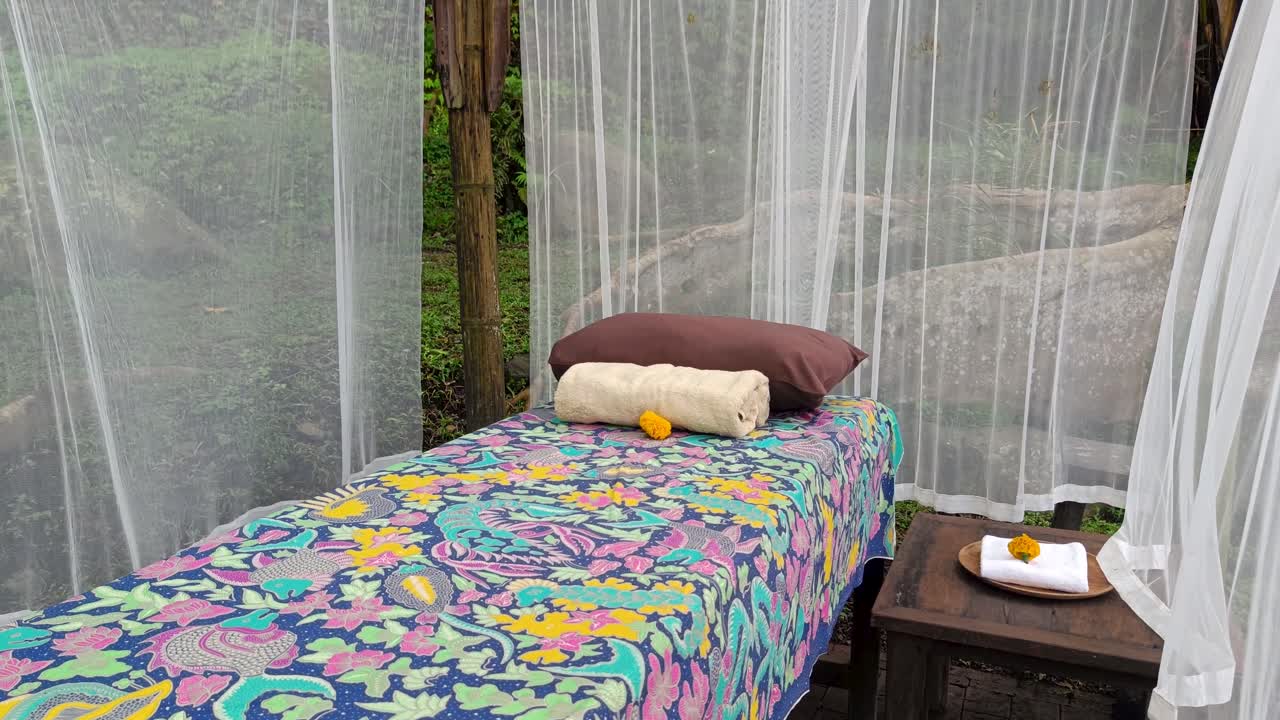 Tempat tidur perawatan spa wellness yang kosong dan damai di hutan tropis terbuka Bali dengan angin bertiup dan relaksasi yang tenang, terbuat dari tirai bambu