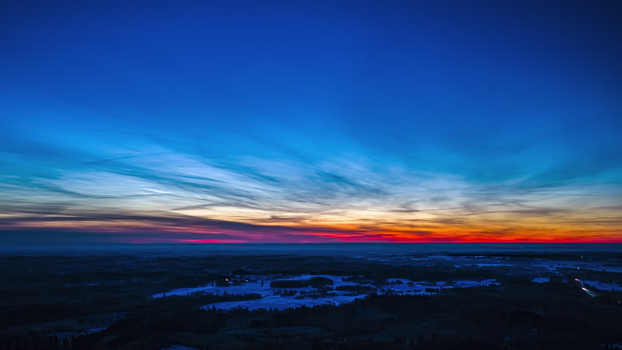 Cielo al tramonto su paesaggio invernale in hyperlapse aereo con fari d'auto sotto, vista ampia