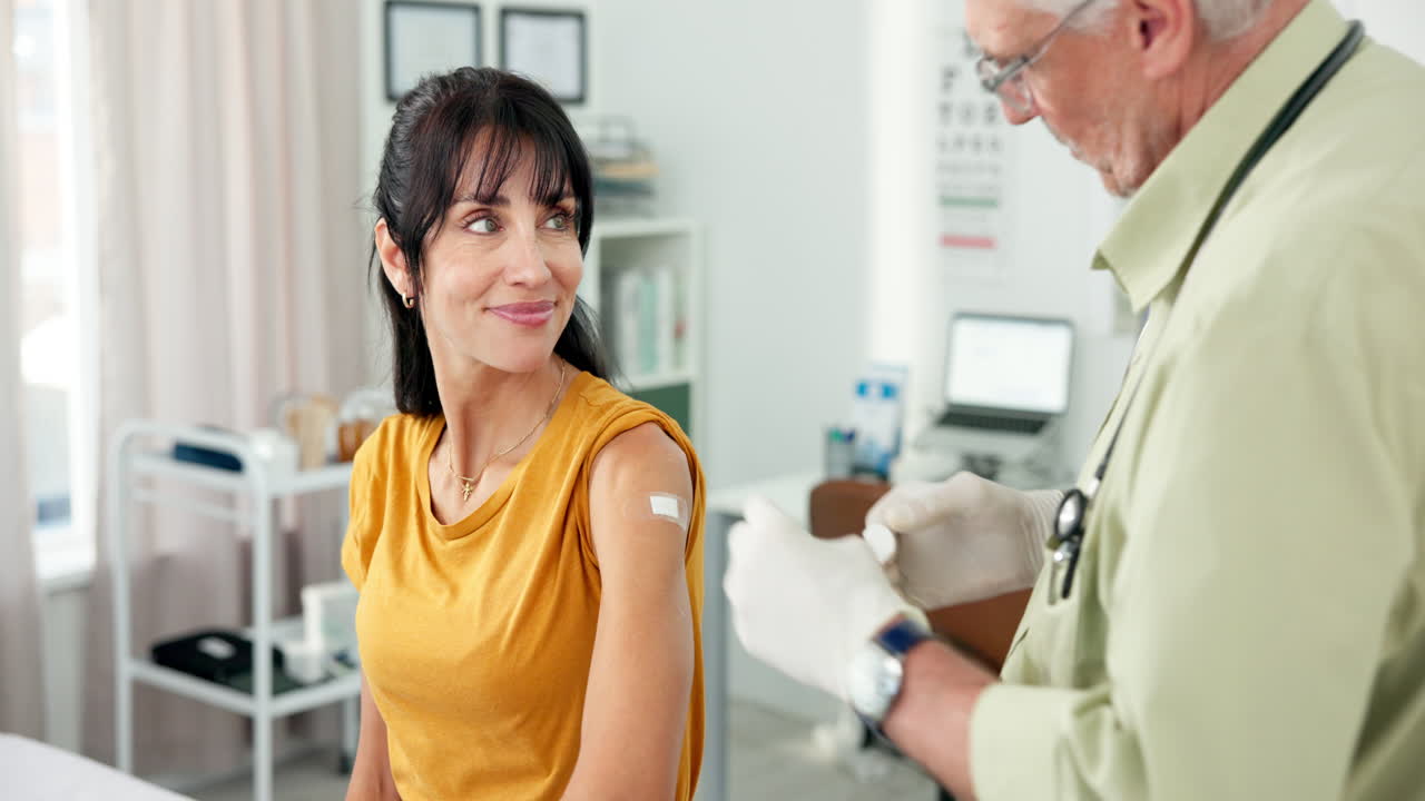 Doctor Applies Bandage to Woman's Arm After Vaccination