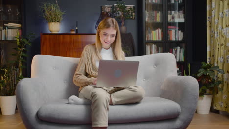 beautiful young woman using laptop computer while sitting on couch at home