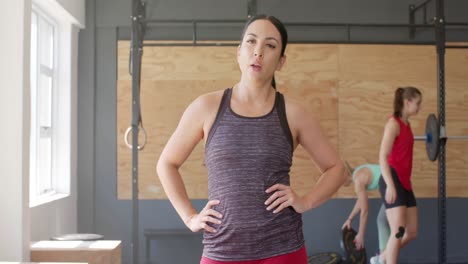 Retrato-De-Una-Mujer-Birracial-Cansada-E-Inalterada-Tomando-Un-Descanso-Del-Entrenamiento-Cruzado-En-El-Gimnasio,-Cámara-Lenta