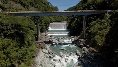 Aerial-Under-Bridge-And-Toward-Man-Made-Waterfalls-In-Kochi-Prefecture-On-The-Island-Of-Shikoku,-Japan