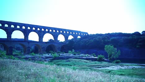 pont du gard in france bridge over a river with meadow in the foreground in good weather