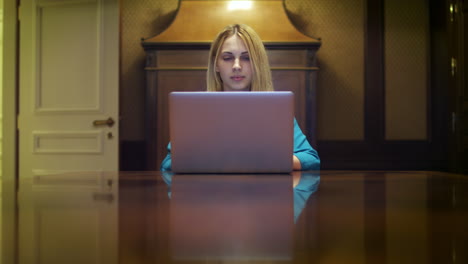 Serious-woman-working-on-notebook-computer-sitting-at-table-in-home-studio