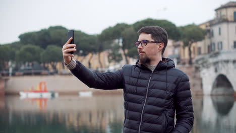 hombre tomando una selfie junto al río en la ciudad