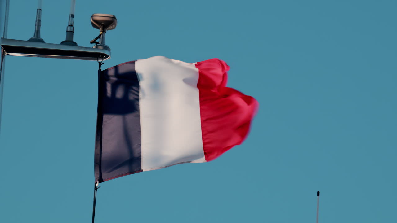 The flag of France waving on a blue sky background