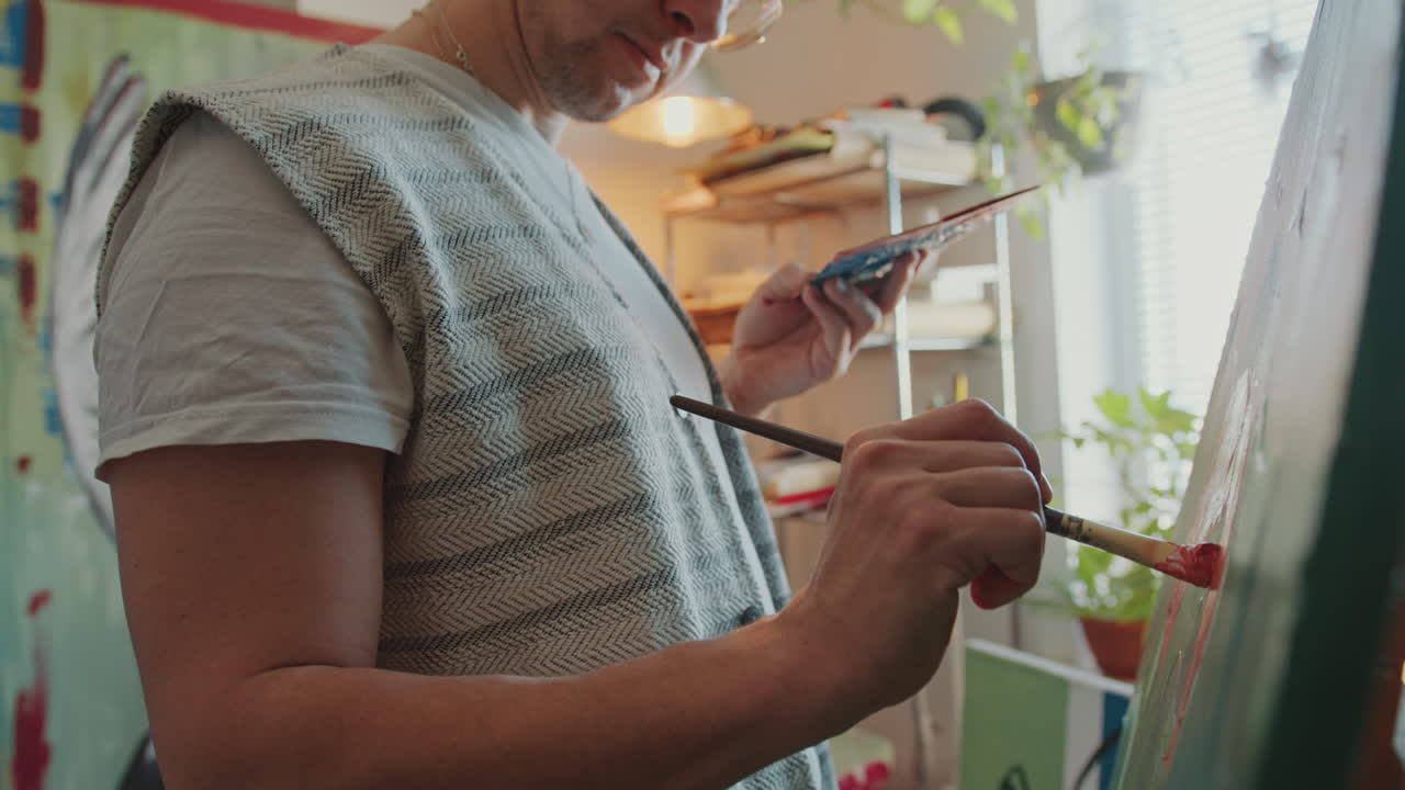 primer plano del artista sosteniendo el pincel y la paleta mientras pinta