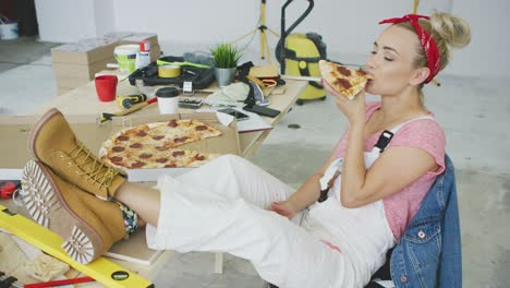 Female-carpenter-eating-pizza-at-workplace