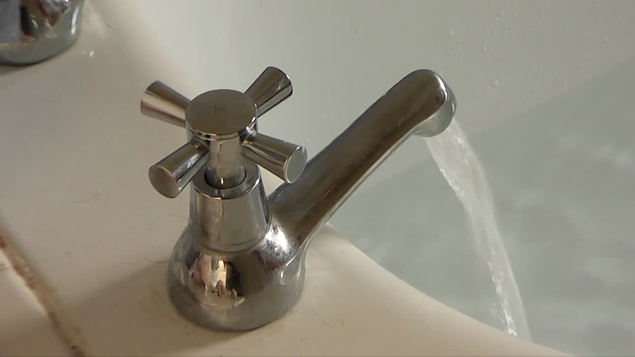 En vandhane lader varmt vand løbe ned i et halvfyldt badekar.