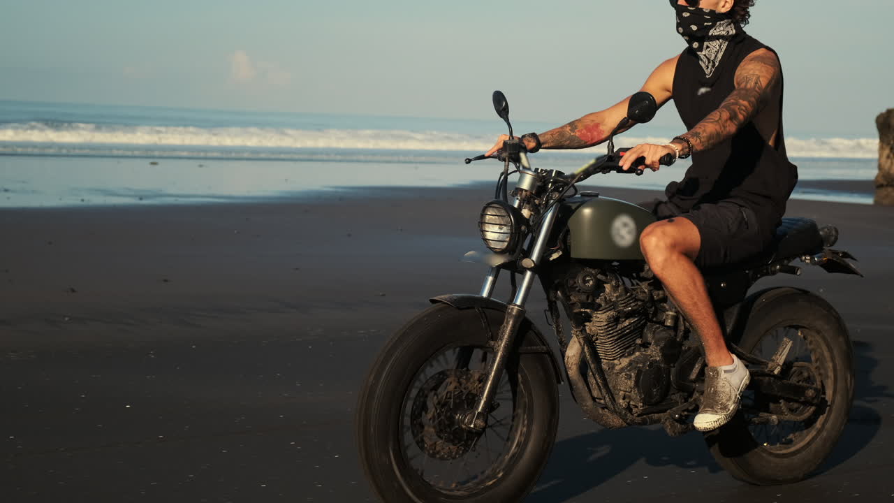 Man Riding Motorcycle on Beach at Sunset