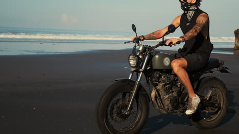 hombre montando una motocicleta en la playa al atardecer