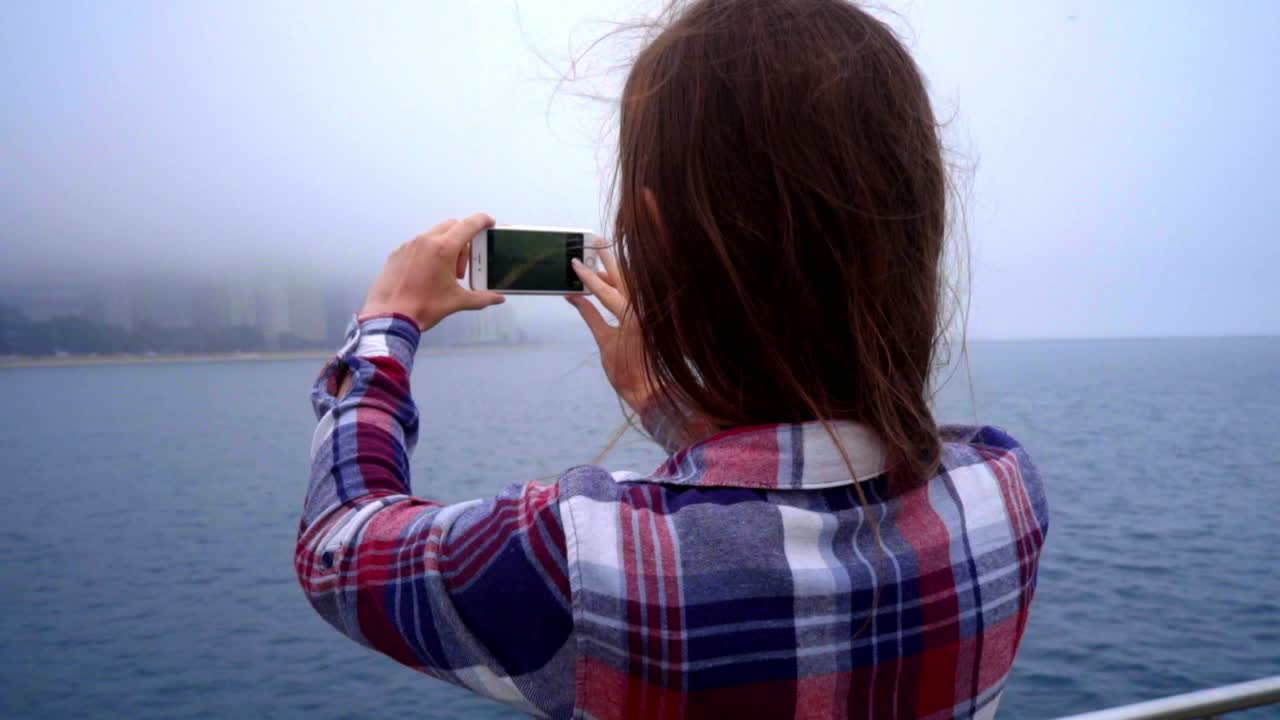 hermosa mujer haciendo una foto móvil de la ciudad moderna en la niebla