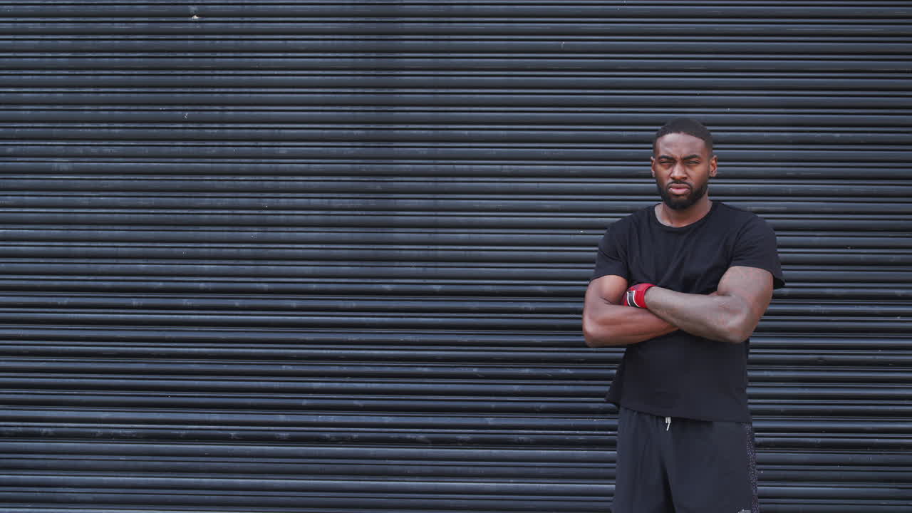 Portrait Of Male Boxer With Wraps On Hands Standing By Metal Shutter Outside Gym