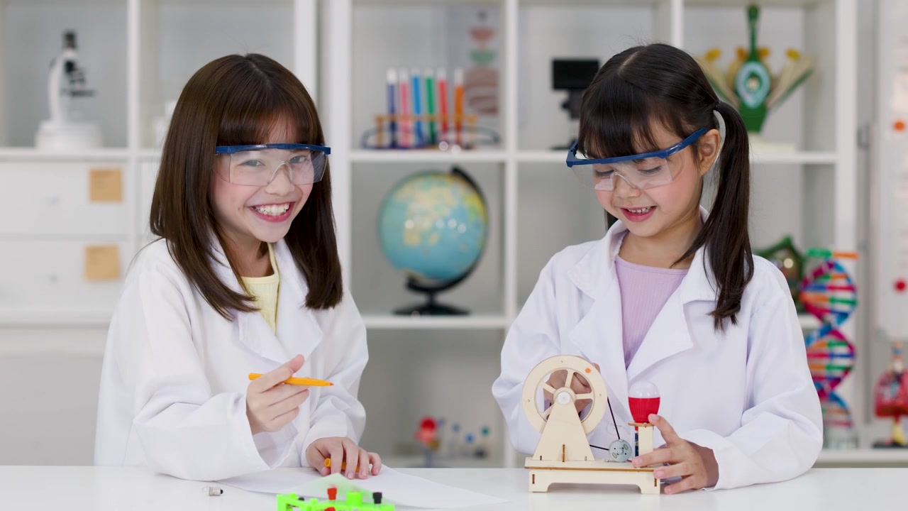 Two students in safety goggles celebrate a successful experiment with a high five in laboratory.