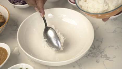 closeup of dipping white jasmine rice to a white bowl delicious vibrant vegan dish