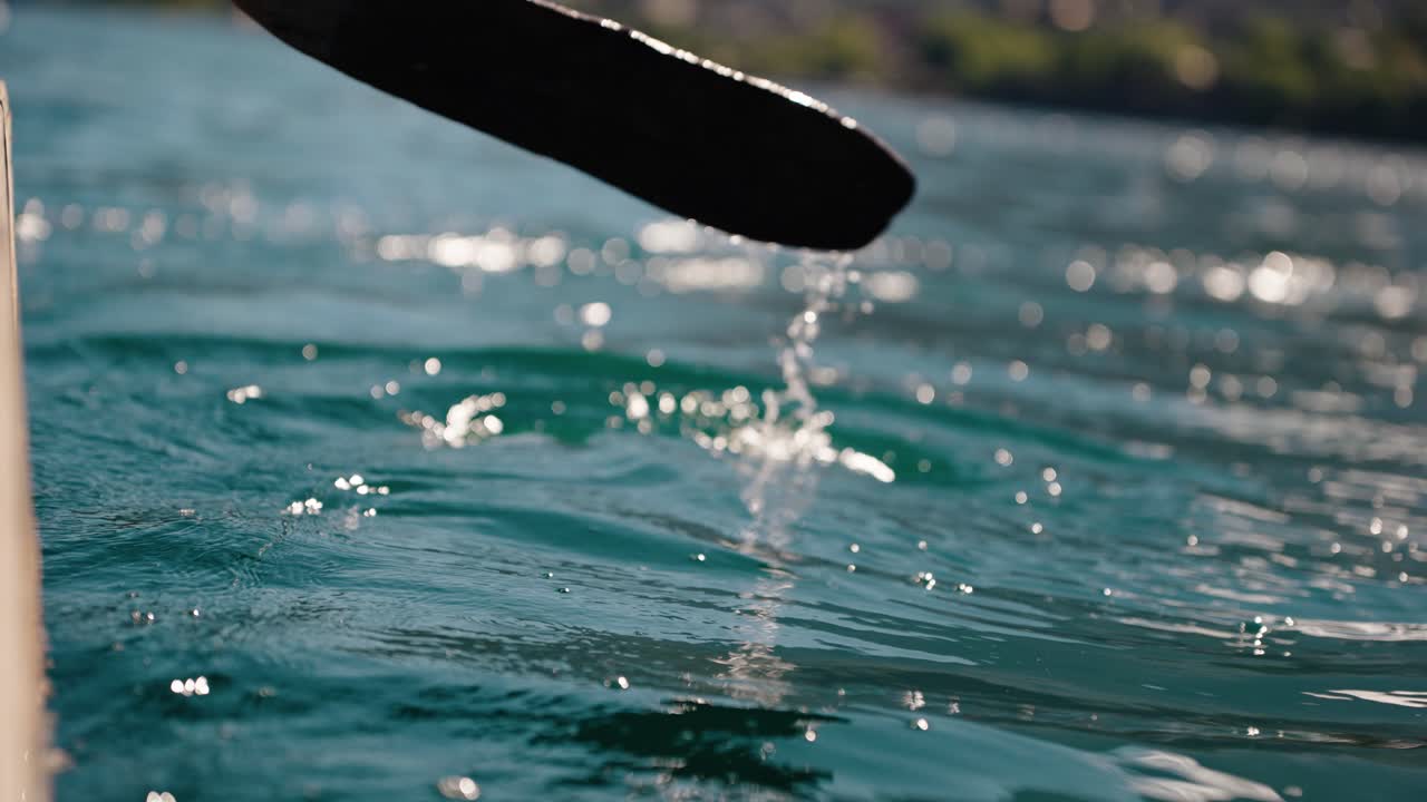 Wooden paddle splashes through clear waters of Lake Atitlán