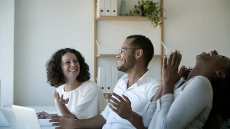 Group-of-successful-workers-talking-and-pointing-at-laptop