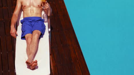 Handsome-man-holding-cocktail-on-deck-chair