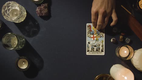 overhead shot of person giving tarot card reading laying down the judgement card on table