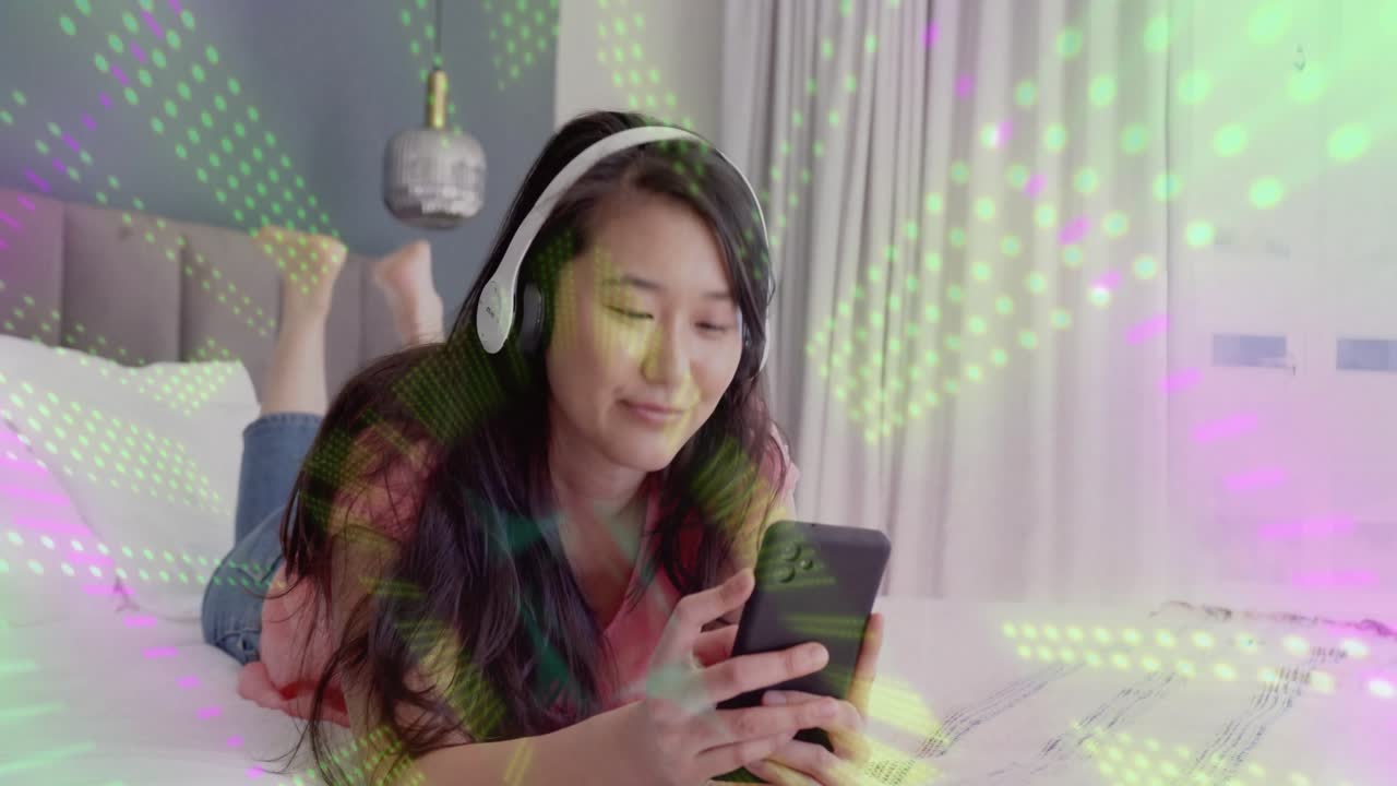 Kvinne på sengen som trykker på smarttelefonen og starter animerte lys-overlegg mens hun ler for underholdning