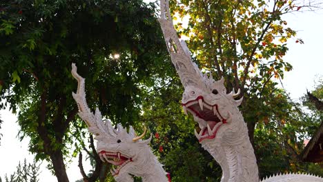 close up of white marbled naga statues with sun flares