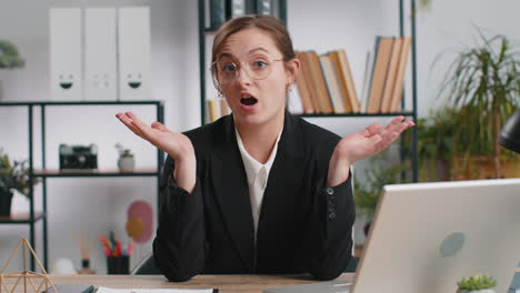 businesswoman in office sitting at her desk, thinking and looking confused