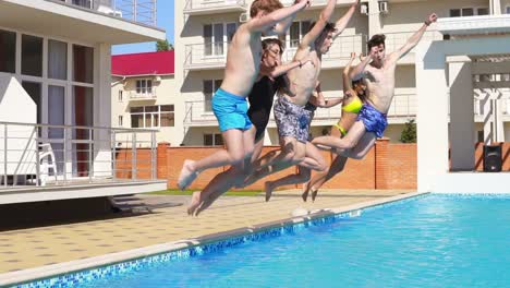 excited group of young attractive people in swimsuits jumping into swimming pool on a summers day. slowmotion shot