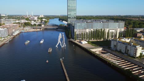 Smooth-aerial-top-view-flight-Molecule-Man-on-border-river-Spree,-east-Berlin-Germany-evening-summer-23