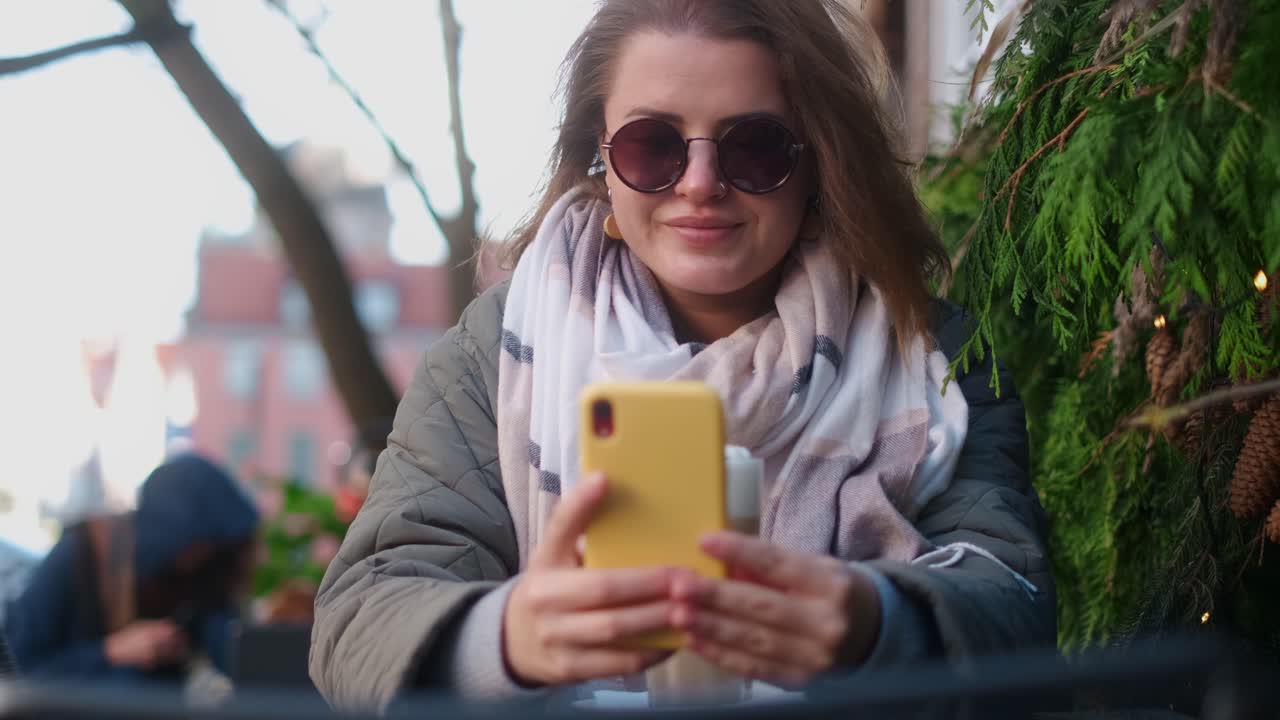 Woman using phone in outdoor cafe