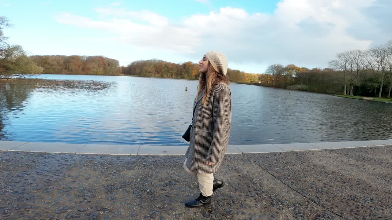 행복한 여자는 화창한 날 겨울에 호수와 카누 가게 옆에서 혼자 걷는다