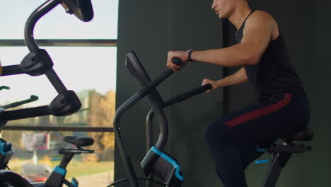 Hombres-Jóvenes-Activos-Haciendo-Girar-Una-Bicicleta-De-Aire-En-El-Gimnasio-Con-Entrenadores.-Entrenamiento-Masculino-En-Bicicleta-De-Aire.