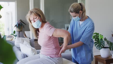 una trabajadora de la salud estirando la espalda de una mujer mayor en casa