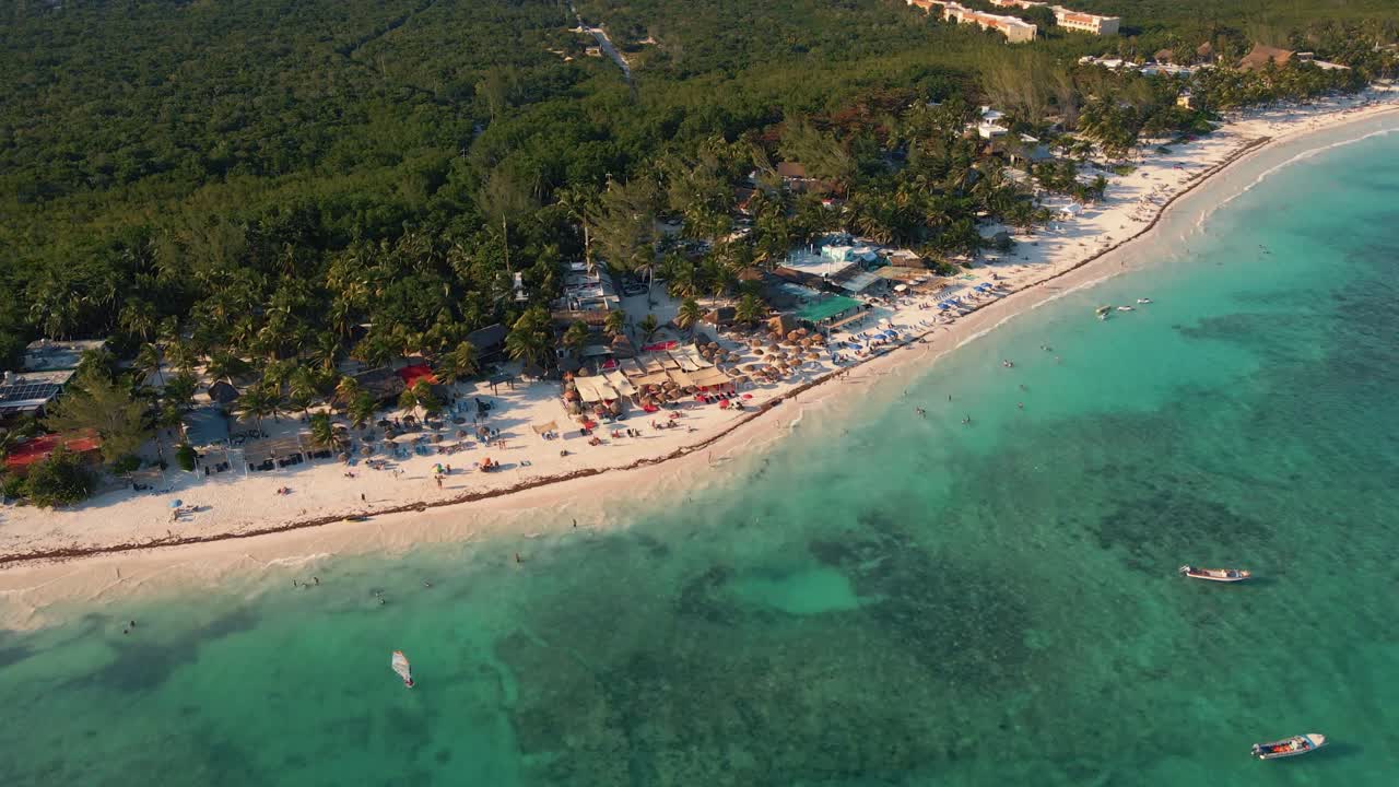 volando sobre las aguas turquesas del mar caribe para revelar la industria turística frente al mar y los hoteles con la densa jungla mexicana al fondo en playa paraíso en tulum méxico