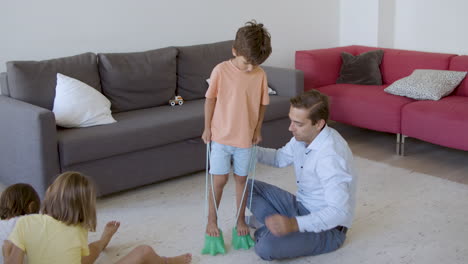 Playful-boy-walking-on-carpet-in-toy-dinosaur-footprints