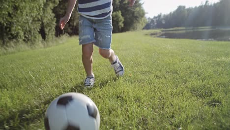 Tracking-video-of-little-boy-playing-football-on-the-grass