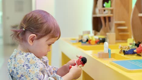 cute korean-ukrainian toddler girl playing with toy figures and a dollhouse