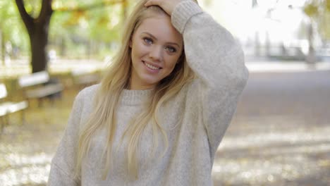 smiling woman smoothing hair in park