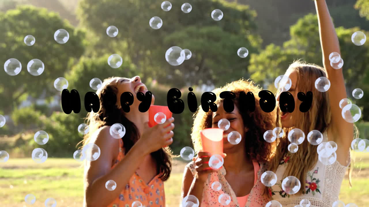 Celebrating birthday outdoors, diverse friends with animation of floating bubbles