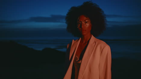 frau, die nachts am strand mit party-make-up posiert. porträt im dunkeln