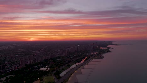 lake michigan shoreline and chicago usa in twilight with purple orange sunset sky in background, aerial view