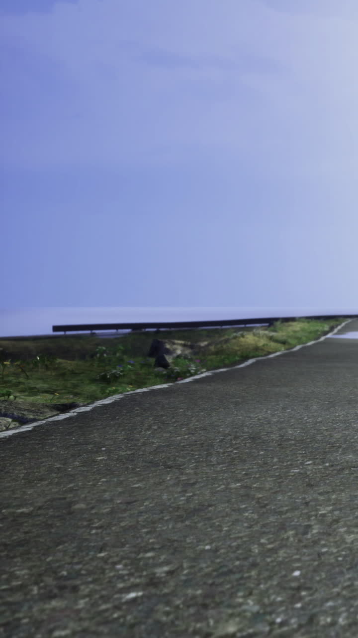 Ampia strada si estende in lontananza vicino alla costa sotto un cielo azzurro limpido.